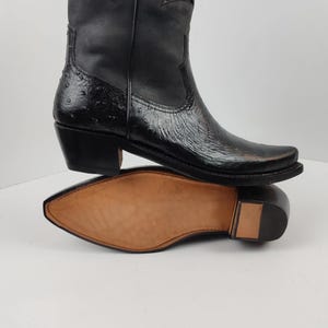 A close-up view of a black leather cowboy boot with a distinctive star-shaped heel design.