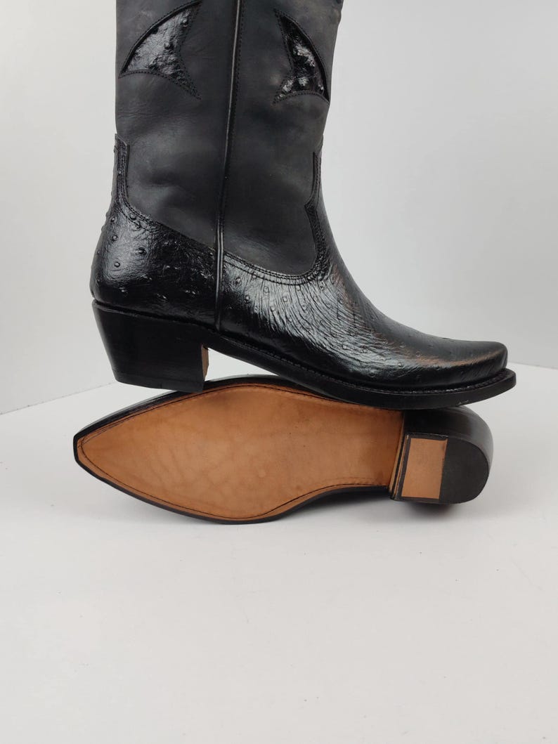 A close-up view of a black leather cowboy boot with a distinctive star-shaped heel design.