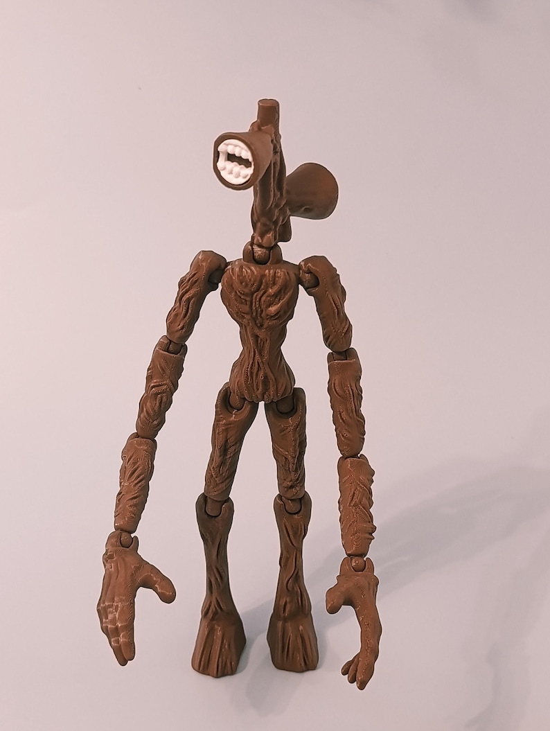 Op de afbeelding: Een bruin Siren Head actiefiguur met een luidsprekerachtige kop en beweegbare ledematen. Het figuur heeft een gedetailleerd, getextureerd ontwerp en staat op een effen achtergrond. De mond is open en toont witte tanden.