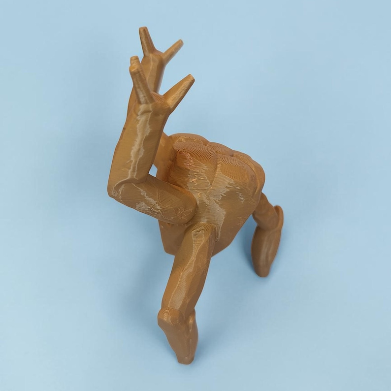 Pode incluir: Escultura impressa em 3D de uma figura humana em pose din&acirc;mica, com os bra&ccedil;os levantados e as pernas estendidas. A figura &eacute; de cor castanha clara e parece ser feita de pl&aacute;stico. O fundo &eacute; azul claro s&oacute;lido.