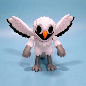 May include: A white owl figurine with outstretched wings, black accents, and an orange beak. The owl has large, round eyes and gray feet and hands. The figurine is set against a light blue background.