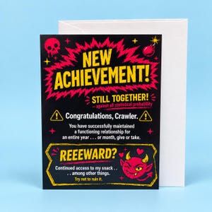 May include: A black greeting card with yellow and pink text reading NEW ACHIEVEMENT! STILL TOGETHER! Congratulations, Crawler. You have successfully maintained a functioning relationship for an entire year. REEEWARD? Continued access to my snack.