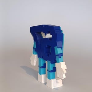 Pode incluir: Uma figura impressa em 3D com um design em blocos. A figura &eacute; principalmente azul, com pernas azul claro e m&atilde;os e p&eacute;s brancos. A figura tem uma est&eacute;tica geom&eacute;trica e pixelizada, sugerindo um tema digital ou retro.
