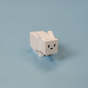 Op de afbeelding: Een witte, blokkerige konijnenfiguur met een minimalistisch ontwerp. Het konijn heeft een rechthoekig lichaam, een vierkante kop en kleine, rechtopstaande oren. De gezichtskenmerken zijn eenvoudige zwarte oog- en monddetails. De figuur staat tegen een lichtblauwe achtergrond.