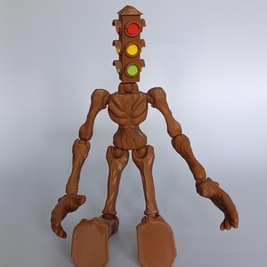 May include: A brown articulated figure with a traffic light head. The figure has a skeletal appearance with visible joints and a torso. The traffic light head features red, yellow, and green lights. The figure is posed on a plain background.