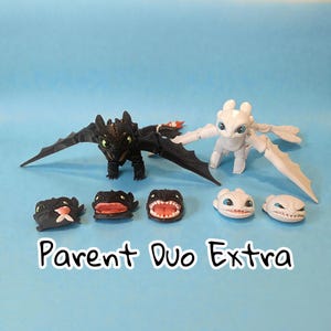 May include: A collection of dragon figurines, including a black dragon with outstretched wings and a white dragon. Several smaller dragon heads with different expressions are also displayed. The text "Parent Duo Extra" is visible.