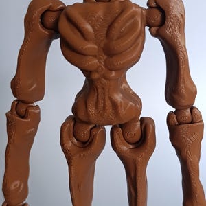 May include: A brown, articulated figure with a skeletal design. The figure has a detailed, textured surface, with visible joints at the shoulders, elbows, hips, and knees. The figure's design resembles a stylized, humanoid form.