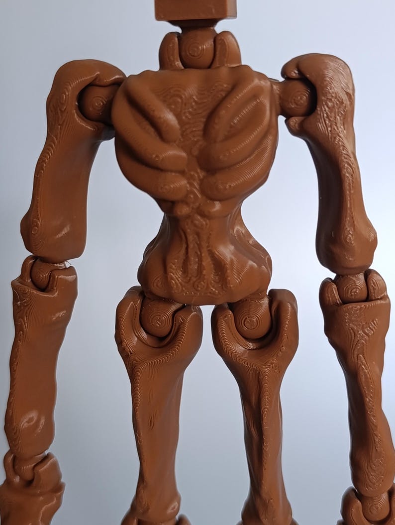 May include: A brown, articulated figure with a skeletal design. The figure has a detailed, textured surface, with visible joints at the shoulders, elbows, hips, and knees. The figure's design resembles a stylized, humanoid form.