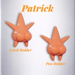 Puede incluir: Dos soportes naranjas con forma de estrella de mar, uno etiquetado como "Card Holder" y el otro como "Pen Holder". La palabra "Patrick" est&aacute; escrita en escritura naranja encima de los soportes. Los soportes tienen un dise&ntilde;o de dibujos animados.