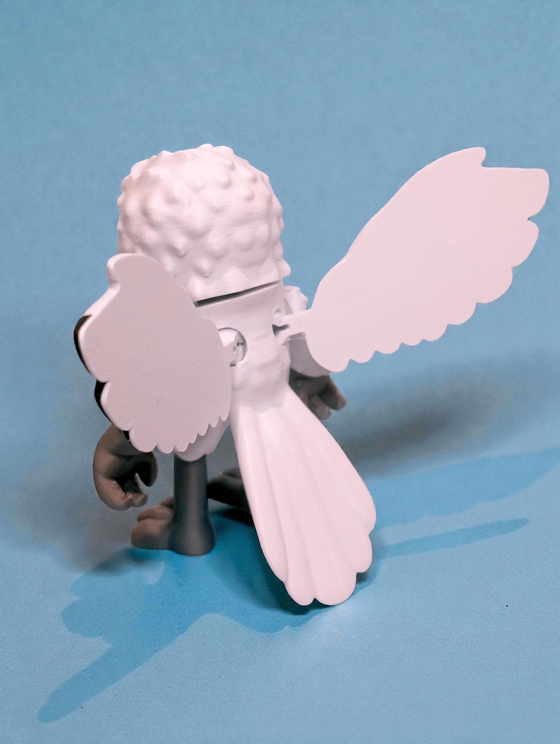 May include: A white figurine of a bird with large, stylized wings and a textured head. The bird has gray legs and a tail, set against a light blue background. The wings are spread, and the figure is viewed from the back.