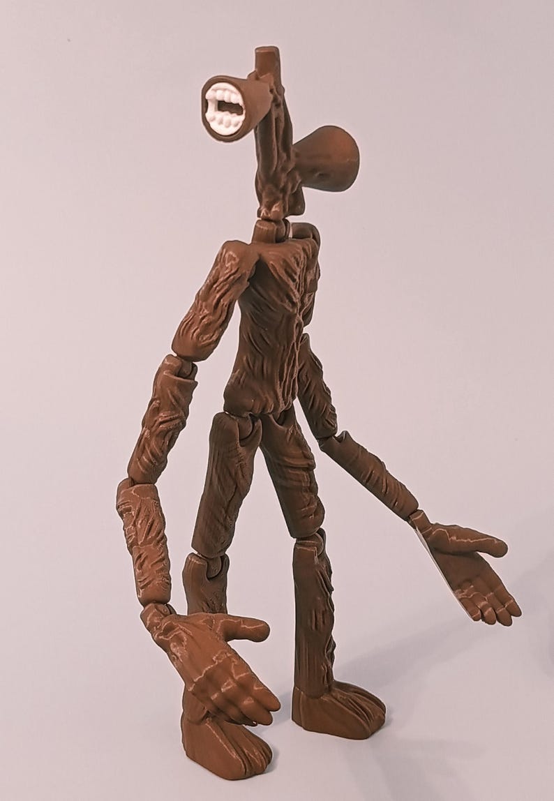 Op de afbeelding: Een bruin Siren Head actiefiguur met een gedetailleerd, getextureerd ontwerp. De figuur heeft een unieke hoofdvorm met een luidspreker en een mond. De armen en benen zijn beweeglijk, en de handen zijn open.