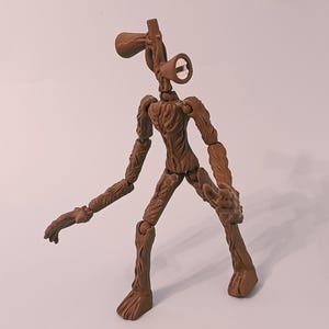 Op de afbeelding: Een bruin Siren Head actiefiguur met beweegbare gewrichten. De figuur heeft een gedetailleerd, gestructureerd ontwerp, met een hoofd in de vorm van twee sirenes. De figuur poseert met &eacute;&eacute;n arm uitgestrekt en de andere gebogen.