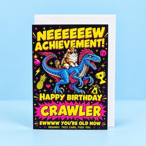 May include: A black greeting card featuring a blue dinosaur with a cat wearing a crown and sunglasses on its back. The text reads: NEEEEEW ACHIEVEMENT! HAPPY BIRTHDAY CRAWLER EWWWW YOU'RE OLD NOW REWARD: THIS CARD, FUCK YOU. Includes icons of a pineapple, trophy, and skull.