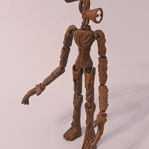 Op de afbeelding: Een bruin Siren Head actiefiguur met een getextureerd, boomachtig uiterlijk. Het figuur heeft twee luidspreker-vormige hoofden en beweegbare ledematen. Het figuur staat op een witte ondergrond.