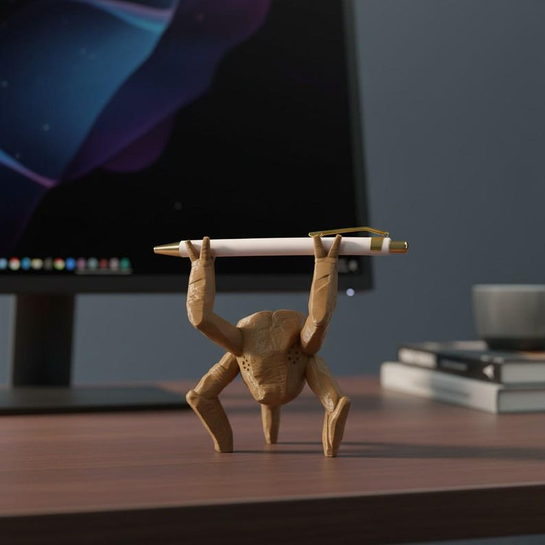 Pode incluir: Um porta-canetas marrom e extravagante em forma de criatura, segurando uma caneta branca com detalhes dourados. O porta-canetas tem uma superf&iacute;cie texturizada e est&aacute; posicionado em uma mesa de madeira. Um monitor de computador e livros est&atilde;o ao fundo.