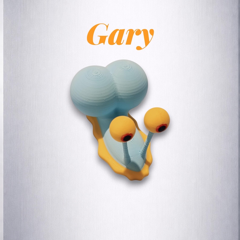 Puede incluir: Una escultura caprichosa de un caracol llamado "Gary". El caracol presenta un cuerpo azul claro, detalles amarillos y dos grandes ojos naranjas con pupilas rojas. La palabra "Gary" est&aacute; escrita en naranja encima del caracol.