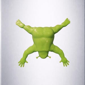 Puede incluir: Una figura de rana verde brillante y estilizada en pose de buceo. La rana tiene los brazos y las piernas extendidos, con un torso musculoso. La figura est&aacute; sobre un fondo gris claro.