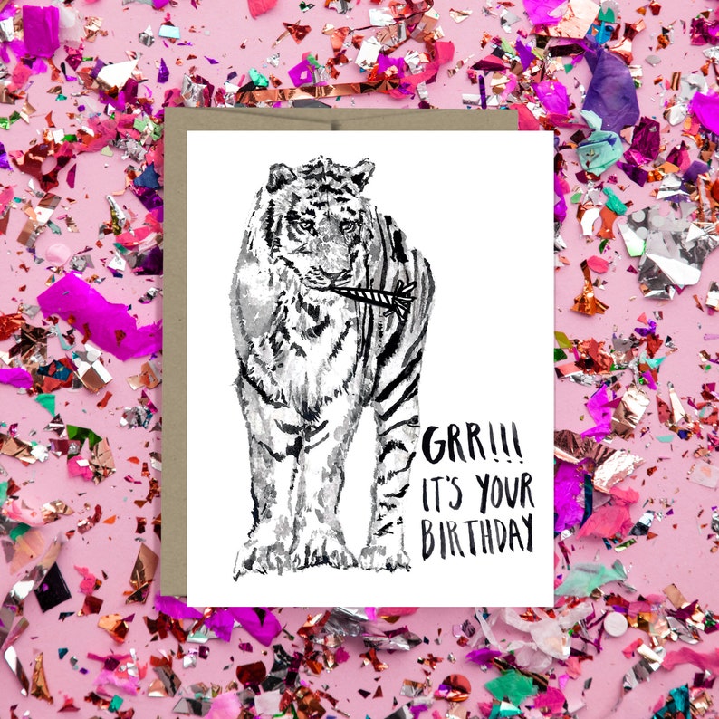 May include: A black and white illustration of a tiger holding a party popper in its mouth. The text "GRR!!! It's your birthday" is written below the tiger.