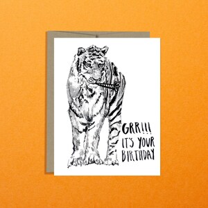 May include: A black and white illustration of a tiger holding a party popper in its mouth. The text "GRR!!! IT'S YOUR BIRTHDAY" is written below the tiger.
