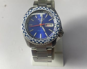 Seiko 5 Automatic Blue Dial Watch with Checkered Bezel – Retro Racing Style – Stainless Steel