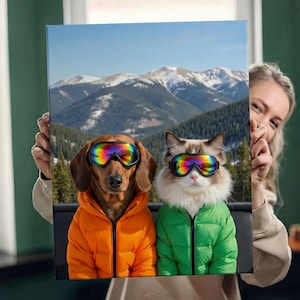 Könnte beinhalten: Leinwanddruck mit einem Dackel und einer Ragdoll-Katze, beide mit regenbogenfarbenen Skibrillen und Steppjacken. Der Dackel trägt eine orangefarbene Jacke, die Katze eine grüne Jacke. Im Hintergrund ist ein Gebirge zu sehen.