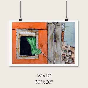 May include: A watercolor painting depicting an orange building facade with a window featuring a green curtain blowing outward. A black street lamp is attached to the adjacent gray wall. The text below reads 18 inches by 12 inches and 30 inches by 20 inches.