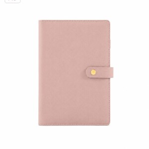 May include: A5 size, light pink planner with a snap closure. The cover is a solid, smooth color. The closure is a small strap with a gold-colored snap. The top left corner has the text "A5".