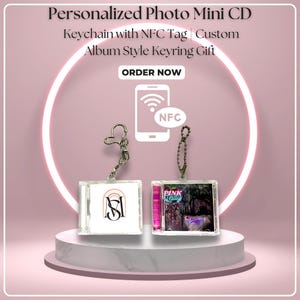 May include: Two mini CD keychains with custom album art, one with a pink and black design and the other with a logo. The keychains are displayed on a white pedestal with a pink background and a neon light ring. The text "Personalized Photo Mini CD Keychain with NFC Tag" is at the top.