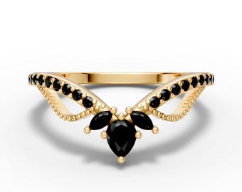 May include: A gold-colored ring with a unique design. The ring features a series of small black stones along the band and a cluster of larger black stones in the center, creating a distinctive, elegant look. The ring is set against a white background.