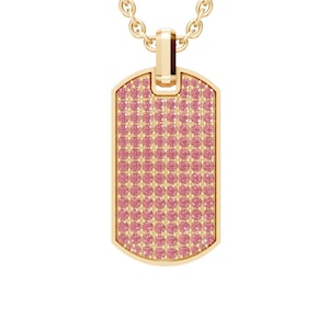 May include: A gold-colored dog tag pendant necklace with a chain. The tag is covered in small pink gemstones. The pendant hangs from a delicate gold chain, creating a classic and elegant look. This necklace is a stylish accessory.