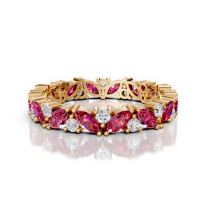 May include: A gold ring with a continuous pattern of marquise-cut pink gemstones and round white gemstones. The ring has a delicate, openwork design on the band, creating a floral-like appearance. The gemstones are set closely together.