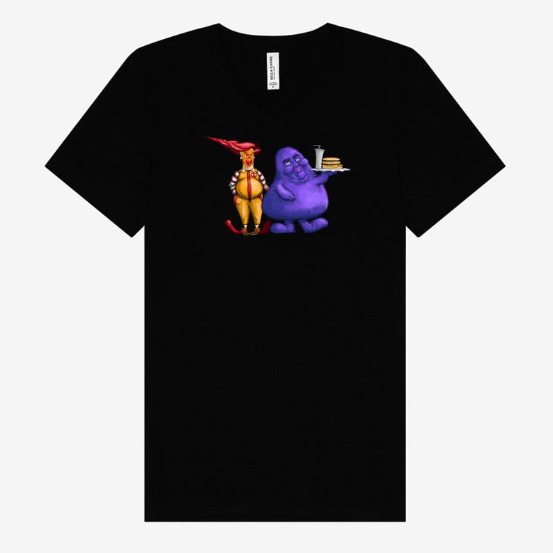 May include: Black V-neck t-shirt featuring a cartoon illustration of two characters. One character is dressed in a yellow and red outfit, and the other is a purple blob holding a tray with a burger and drink.