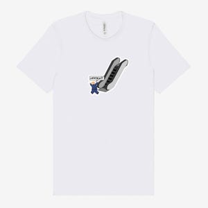 May include: White t-shirt featuring a cartoon graphic of a person in a blue suit falling down an escalator. The speech bubble says "UPPIES!!!". The shirt is made of a soft, comfortable material.