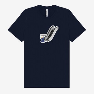 May include: Navy blue t-shirt featuring a cartoon graphic of an escalator with a person waving and the text "UPPIES!!!". The graphic is in shades of gray, white, and blue. The shirt is a classic crew neck.