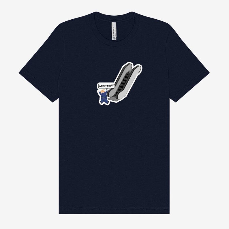 May include: Navy blue t-shirt featuring a cartoon graphic of an escalator with a person waving and the text "UPPIES!!!". The graphic is in shades of gray, white, and blue. The shirt is a classic crew neck.
