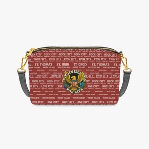 May include: A rectangular crossbody bag in a deep red hue, featuring a repeating white text pattern of Virgin Islands locations like St. Thomas and St. Croix. A central circular emblem displays a golden eagle with the text Virgin Islands For Life.
