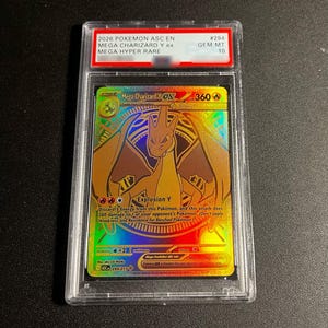 May include: A graded 2026 Pokemon ASC EN Mega Charizard Y ex trading card in a clear plastic slab. The card features a gold-toned holographic illustration of the dragon-like creature with 360 HP and the text Explosion Y. The label reads GEM MT 10.