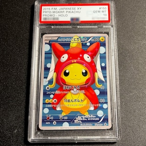 May include: A graded Pokémon card featuring Pikachu in a red Magikarp costume. The card has Japanese text and is labeled "2015 P.M. JAPANESE XY PRTD.MGKRP. PIKACHU PROMO - HOLO." The card is graded GEM MT 10.