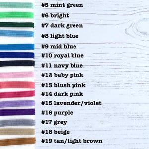 May include: A chart with 22 different colored elastic bands, each labeled with a number and a color name. The colors include red, orange, yellow, green, blue, pink, purple, grey, beige, brown, and white.