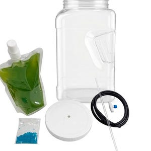 May include: A clear plastic container with a white lid, a black tube with a blue valve, a clear straw, a pouch of green liquid, and a small bag of blue granules. The container has a handle-like indentation.