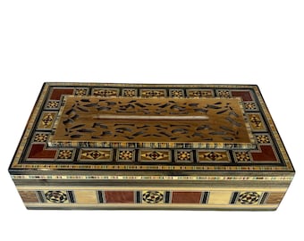 May include: Rectangular wooden box with intricate inlaid patterns in shades of brown, red, black, and cream. The lid features a carved design and geometric borders, showcasing a detailed craft. The box is likely used for storage or display.