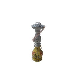 May include: A decorative hookah with a silver-colored top and a yellow base. The base is adorned with red and yellow floral designs. A silver chain is attached to the top.