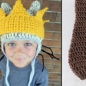May include: A child wearing a crocheted hat with a yellow crown and black yarn whiskers. The hat has a gray and white brim. The child is wearing a gray shirt.