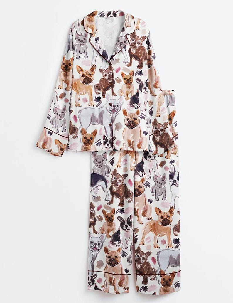 K&ouml;nnte beinhalten: Eine wei&szlig;e Keramik-Tasse mit schwarzem Henkel und dem Text "But First, Coffee" in fetter, schwarzer Schrift. Die Tasse steht vor einem verschwommenen Hintergrund, der eine gem&uuml;tliche Umgebung andeutet.