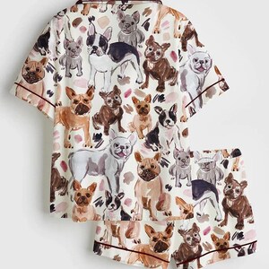 K&ouml;nnte beinhalten: Wei&szlig;es Pyjama-Set mit einem sich wiederholenden Muster verschiedener Franz&ouml;sische Bulldogge-Illustrationen in Braun-, Schwarz- und Graut&ouml;nen. Das kurz&auml;rmelige Oberteil und die Shorts haben bordeauxfarbene Paspeln.
