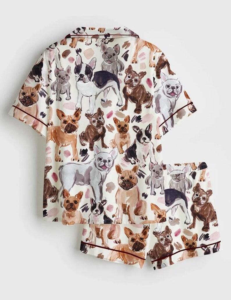K&ouml;nnte beinhalten: Wei&szlig;es Pyjama-Set mit einem sich wiederholenden Muster verschiedener Franz&ouml;sische Bulldogge-Illustrationen in Braun-, Schwarz- und Graut&ouml;nen. Das kurz&auml;rmelige Oberteil und die Shorts haben bordeauxfarbene Paspeln.