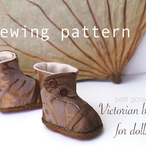 Puede incluir: Patrón de costura para botas victorianas para muñecas. El patrón incluye dos botas marrones con un diseño de tela dorada y botones marrones. Las botas están sobre una superficie blanca con una hoja seca en el fondo.