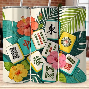 May include: A white tumbler featuring a vibrant design of Mahjong tiles, tropical flowers, and lush green leaves. The design includes orange, yellow, and pink hibiscus flowers, and various Mahjong tiles with Chinese characters.