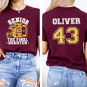 May include: A maroon t-shirt featuring a front graphic with a football helmet, the text SENIOR MOM THE FINAL QUARTER, and the number 43. The back of the shirt displays the name OLIVER in white letters above the large gold number 43 with a white outline.