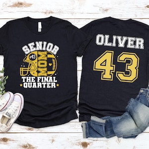 May include: A black short-sleeved t-shirt featuring a yellow and white graphic on the front with a football helmet, the text SENIOR MOM THE FINAL QUARTER, and the number 43. The back displays the name OLIVER and the large yellow number 43.